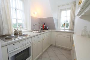 a white kitchen with a sink and a stove at Inselruhe Munkmarsch in Munkmarsch