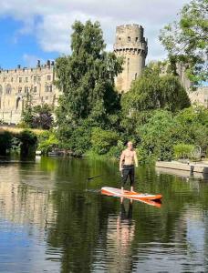 a man on a paddle board in the water in front of a castle at 4 Mellors Court in Warwick