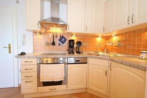 a kitchen with white cabinets and a stove top oven at App. Hackmack 62 in Westerland