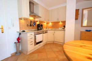 a kitchen with white cabinets and a wooden floor at App. Hackmack 62 in Westerland