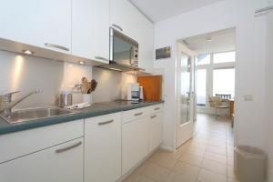 a kitchen with white cabinets and a sink at Haus am Meer14 - App. 159 in Westerland
