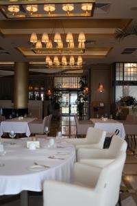 un restaurant avec des tables et des chaises blanches et un lustre dans l'établissement KADORR Hotel Resort & Spa, à Odessa