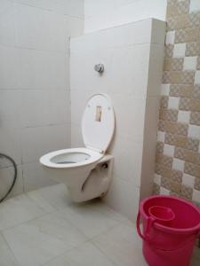 a bathroom with a toilet and a red bucket at Ambassador Hotel in Guwahati
