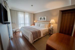 a hotel room with a bed and a flat screen tv at George V Alto De Pinheiros in Sao Paulo