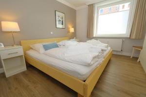 a bedroom with a bed with white sheets and a window at App König 01 in Westerland (Sylt)