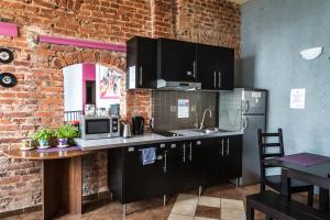 a kitchen with black cabinets and a brick wall at Music Hostel Piotrkowska in Łódź