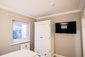ヴェニングシュテットにあるAusternperle 3aの白いキャビネットと薄型テレビ付きのベッドルーム1室が備わります。