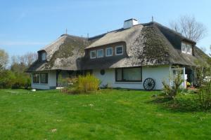 a house with a thatched roof on a yard at Teewelkenhüs Sonnenappartement in Archsum