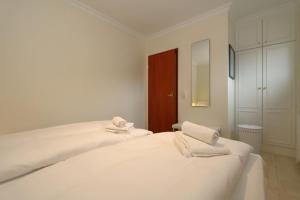 Un dormitorio blanco con una cama grande con toallas. en Alice - Weigel, en Westerland