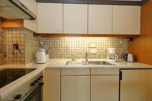 una cocina con armarios blancos y fregadero en Haus Alice - Riebschläger 34-7 en Westerland
