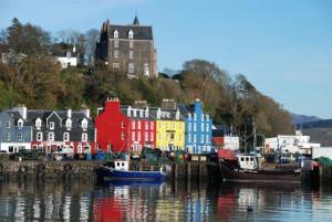 a group of colorful buildings and boats in the water at Harbour Guest House in Tobermory