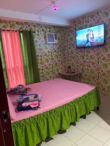 a bedroom with a pink bed with a tv on the wall at 1-BR Condo Unit Urban Deca Homes Manila in Manila
