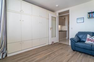 a living room with white cabinets and a blue couch at Haus Sylter Welle 10-105 WB in Westerland (Sylt)