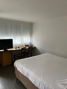 1 dormitorio con 1 cama y escritorio con ordenador en Hôtel Campanile Cahors en Cahors