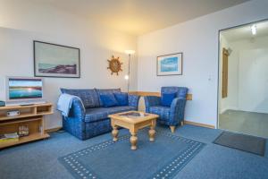 uma sala de estar com um sofá azul e uma televisão em Haus Metropol 196 OB em Westerland