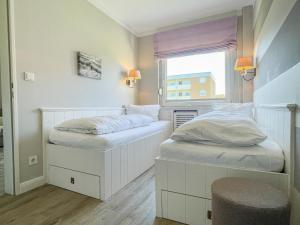 Duas camas brancas num quarto com uma janela em App. Theo 50 em Westerland