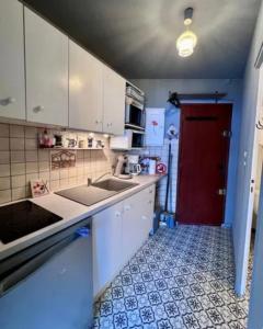 a kitchen with a sink and a red door at Avec balcon, au pied des pistes et randos in Villard-de-Lans