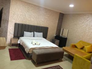 a bedroom with a large bed with a chair and a couch at Hotel Tidinit in Guelmim