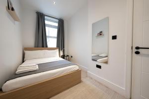 małą sypialnię z łóżkiem i lustrem w obiekcie The Battersea Scenery - Elegant 2BDR Flat w Londynie