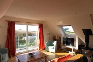 una sala de estar con una gran ventana con cortinas rojas en The Orchard, en Hartland