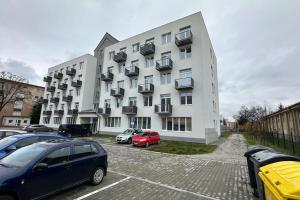 a large white building with cars parked in a parking lot at 1 room Apartment with balcony, Nálepkova 4/6 in Liptovský Mikuláš