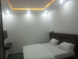 a bedroom with a white bed with two pillows at Skenyo Hotel & Apartments in Ketti