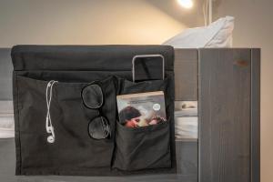 eine schwarze Tasche mit einem Buch und einer Brille auf dem Bett in der Unterkunft Göteborg Hostel in Göteborg