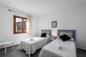 a bedroom with two beds and a window at Historic Pollensa Townhouse - Casa Bugera - 3 Bedrooms - Private Pool - Walking Distance to Centre in Pollença