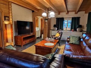 a living room with leather furniture and a flat screen tv at Chalet Familienzeit in Lathum