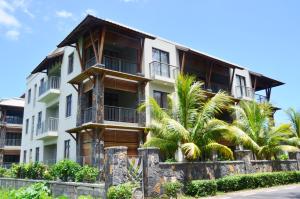 un edificio con palmeras delante en West Terraces Residence No 5 with SEAFRONT - LICENSED BY TOURISM AUTHORITY 13516, en Flic en Flac