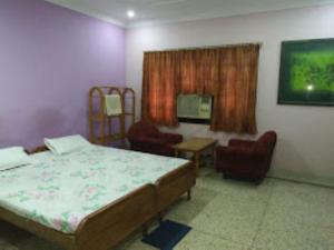 a bedroom with a bed and chairs and a television at PARK VIEW PALACE,Bhubaneswar in Bhubaneshwar