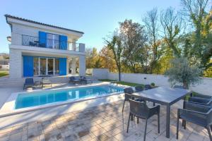 a villa with a swimming pool and a table and chairs at Villa Valle in Sveti Vid-Miholjice