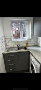a kitchen with a sink and a washing machine at No 2 at Mannering, Large 1 bed near Lark Lane in Liverpool