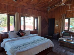 a bedroom with a large bed in a room with windows at Alinda House Naukuchiatal by THE GHAUR in Bhīm Tāl