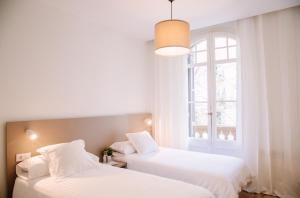 two white beds in a room with a window at Hostalet de Barcelona in Barcelona