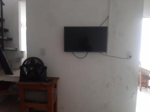 TV de pantalla plana colgada en una pared blanca en Hostel positivo en Buenos Aires