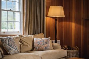 sala de estar con sofá, lámpara y ventana en Coulin Farmhouse, en Kinlochewe