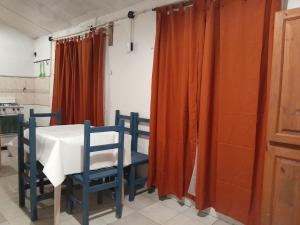 uma mesa de jantar com 2 cadeiras e cortinas cor de laranja em Los Aloes, Casa de campo em Las Toninas