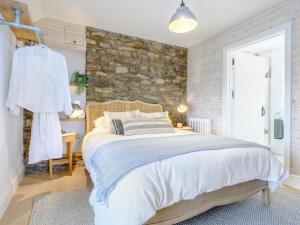 a bedroom with a bed and a stone wall at 2 Bed in Ogmore-by-Sea 86495 in Southerndown