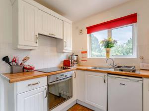 uma cozinha com armários brancos, um lavatório e uma janela em 1 Bed in Ashford-in-the-Water 87471 em Great Longstone