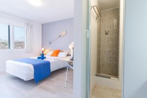 sypialnia z łóżkiem i szklanymi drzwiami w obiekcie Hostel Neon Tenerife w mieście Guaza