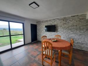 - une salle à manger avec une table, des chaises et une télévision dans l'établissement Mirada al Champaqui, à Villa Yacanto