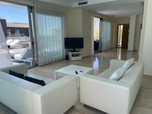 sala de estar con sofás blancos y TV en Altos de Finestrat, en Finestrat