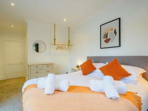 基普福德的住宿－3 Bed in Kippford 88274，一间卧室配有带橙色和白色枕头的床
