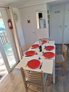 una mesa de comedor con platos rojos. en Mobile home Chic, en Canet-en-Roussillon