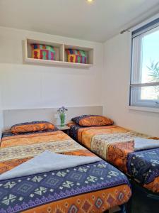 a room with two beds and a window at Mobile home Chic in Canet-en-Roussillon