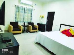 a bedroom with a bed and two chairs and a table at Hotel Rajdhani Roxy,Bhubaneswar in Bhubaneshwar