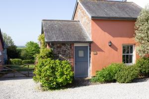 a small red and orange house with a blue door at The Dairy in Hartland