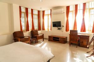 a bedroom with a bed and a desk and a tv at Aestus Adventure and Wellness Centre in Kasauli