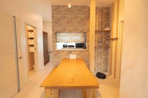 una mesa de madera en una habitación con una pared de ladrillo en furano ski rabi en Furano